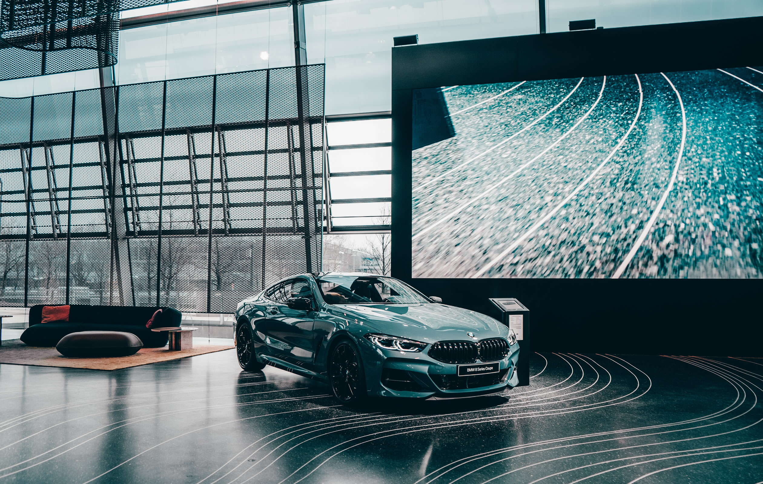Luxury car in a modern showroom beside a large LED video wall.