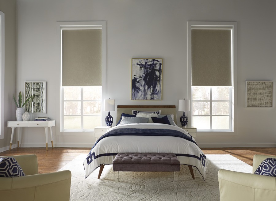 Photo of a bedroom with the bed placed between two vertically long windows, each fitted with motorized shades. 