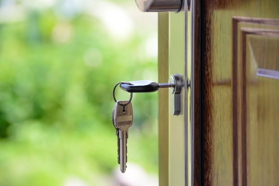 A traditional key hanging from the lock on the front door of a home.